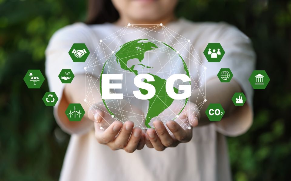 Symboliczne przedstawienie ESG – dłonie trzymające kulę ziemską otoczoną ikonami związanymi ze zrównoważonym rozwojem