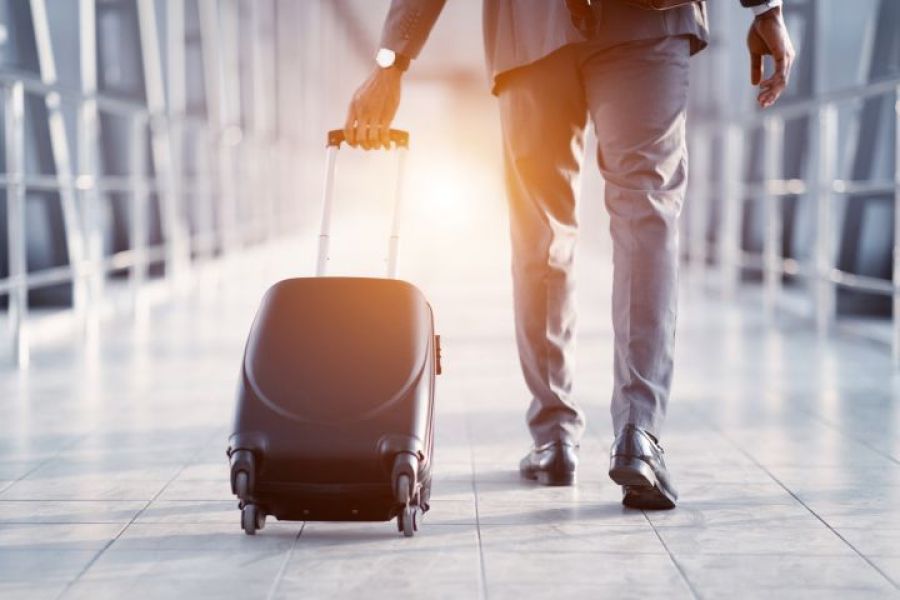 The picture shows a man at the airport with a luggage in his hands