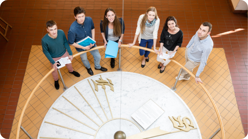 Grupa studentów stojąca przy dużym Wahadłe Foucaulta