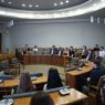 Grupa nagrodzonych osób siedzi w Sali Senatu UAM