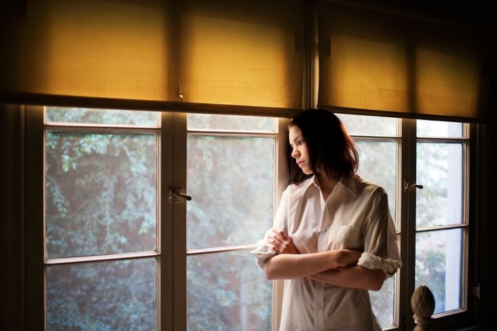 Kobieta wypatrująca przez okno