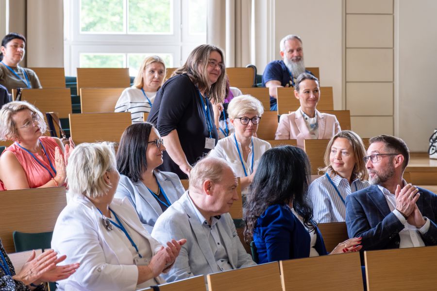 Grupa uczestników konferencji w sali wykładowej.