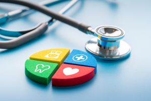  A stethoscope laying next to tiles with icons depicting: a tooth, a nurse, a medical cross and a heart.
