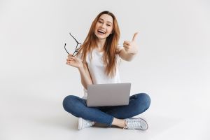  A smiling girl sitting on the floor with a laptop