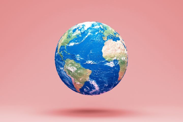 Grafika przedstawiająca kulę ziemską unoszącą się na jasnoróżowym tle.