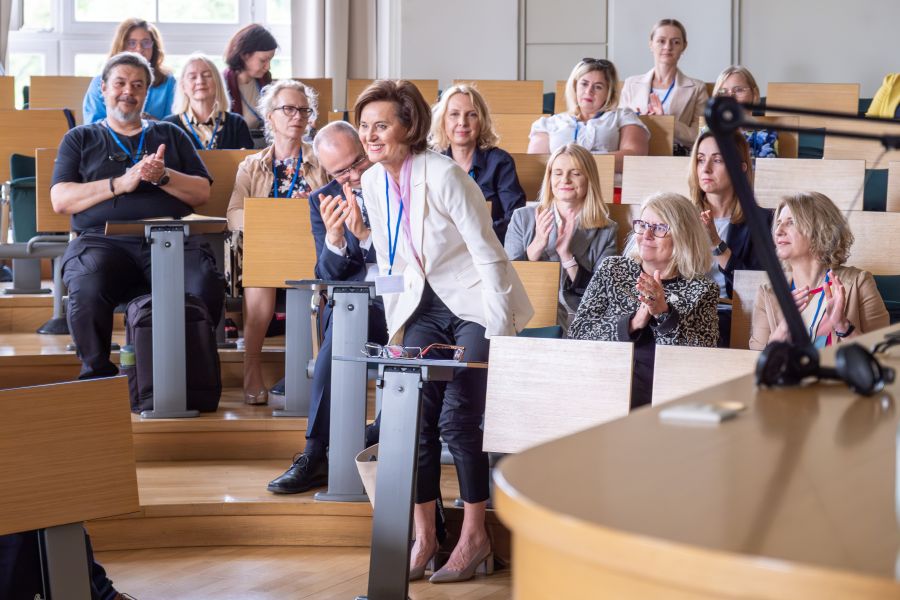 Grupa uczestników konferencji w sali wykładowej.