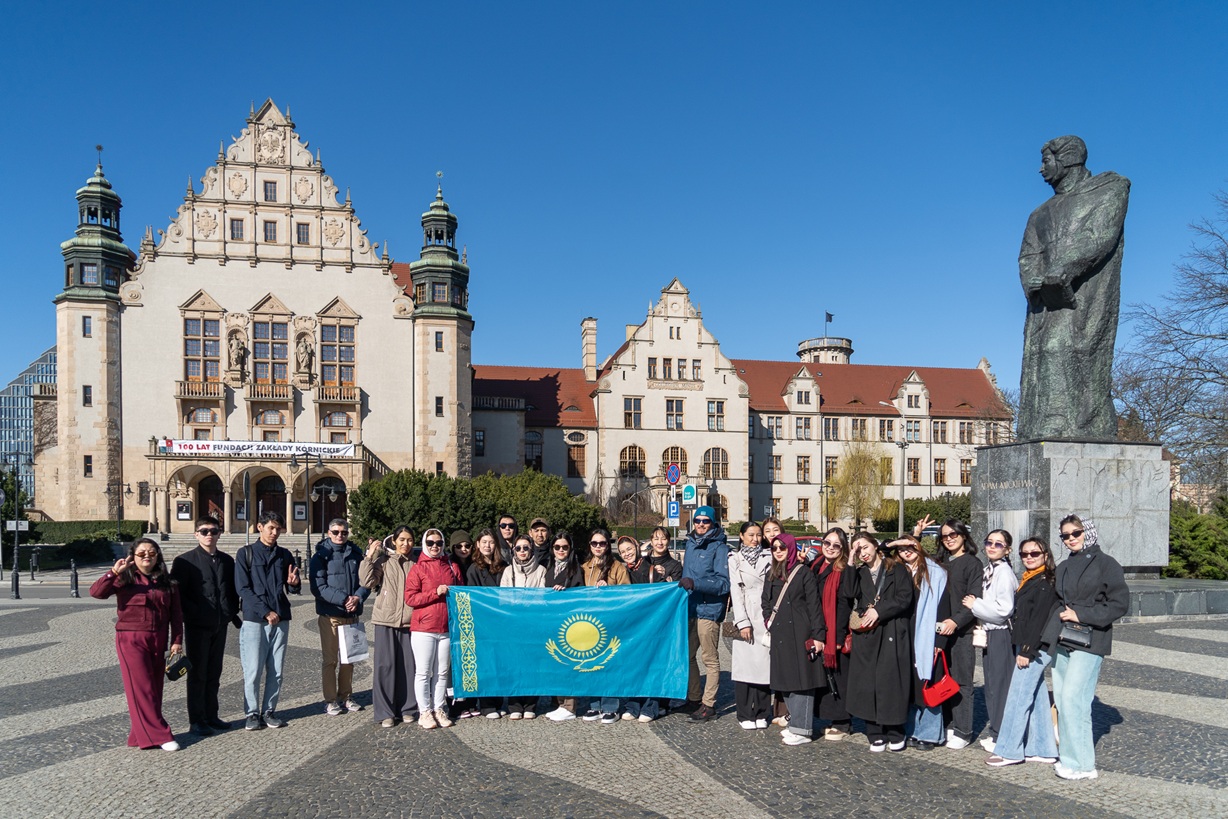 Internship participants in front of the AMU Collegium Minus posing to the group picture with Kazakhstan Flag