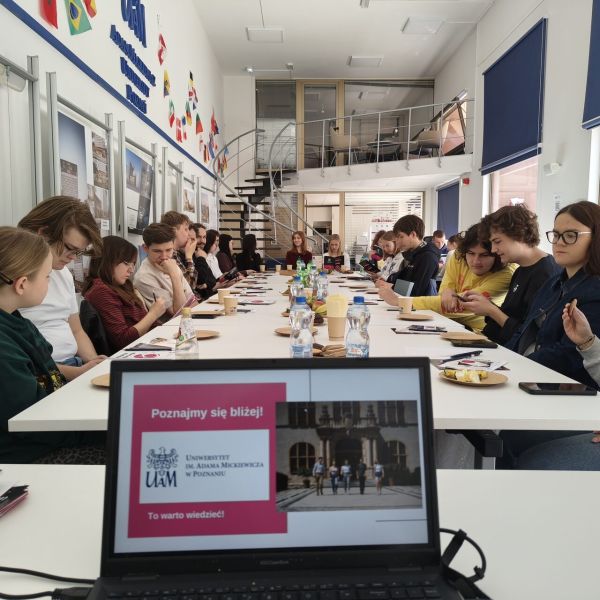 Grupa młodych ludzi siedząca przy stołach