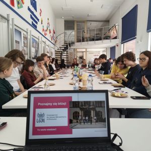 Grupa młodych ludzi siedząca przy stołach