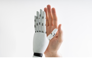 A human hand juxtaposed with a white robotic hand against a light background