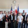 Uczestnicy delegacji, zdjęcie grupowe przed flagami: UE, Polski i USA