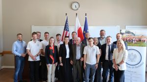 Uczestnicy delegacji, zdjęcie grupowe przed flagami: UE, Polski i USA