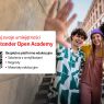 Grafika promująca Santander Open Academy. Po lewej stronie biały prostokąt z czerwonym nagłówkiem ‘Rozwijaj swoje umiejętności na Santander Open Academy’, kodem QR i tekstem: ‘Bezpłatna platforma edukacyjna – szkolenia z certyfikatami, nagrody, materiały edukacyjne’. Po prawej stronie trójka młodych, uśmiechniętych osób obejmujących się i machających do aparatu na tle miejskiej ulicy.