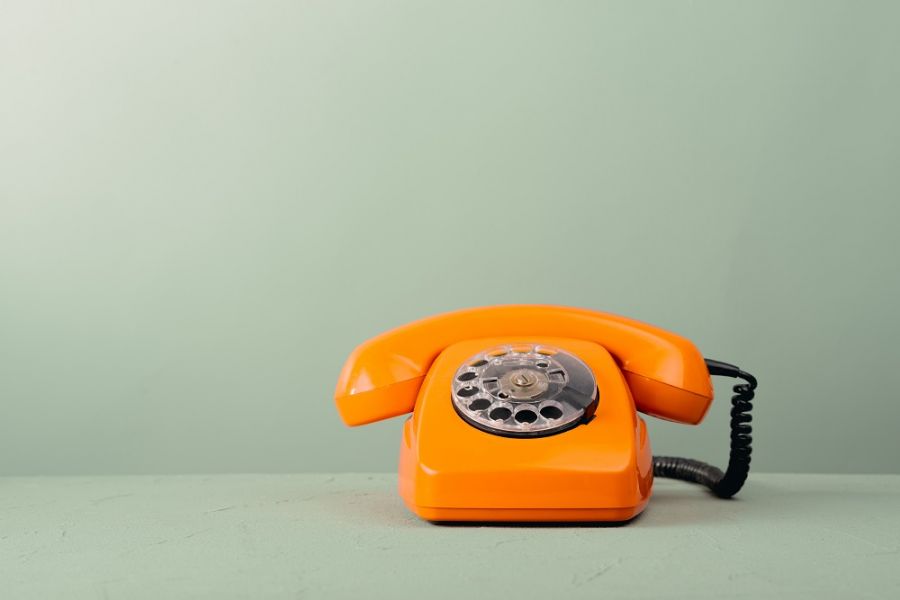 Telefon stacjonarny w kolorze pomarańczowym na zielonym tle