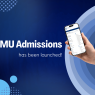 Promotional graphic announcing that “AMU Admissions has been launched!” The design features a dark blue gradient background with abstract circular and dotted geometric elements in light blue shades. On the right side, a hand holds a smartphone displaying the AMU admissions website interface. Large white text on the left reads “AMU Admissions,” with smaller text underneath saying “has been launched!” The overall style is modern, minimal, and technology-focused.